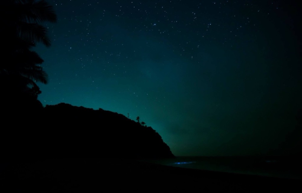 Faint glow on a dark shoreline at night