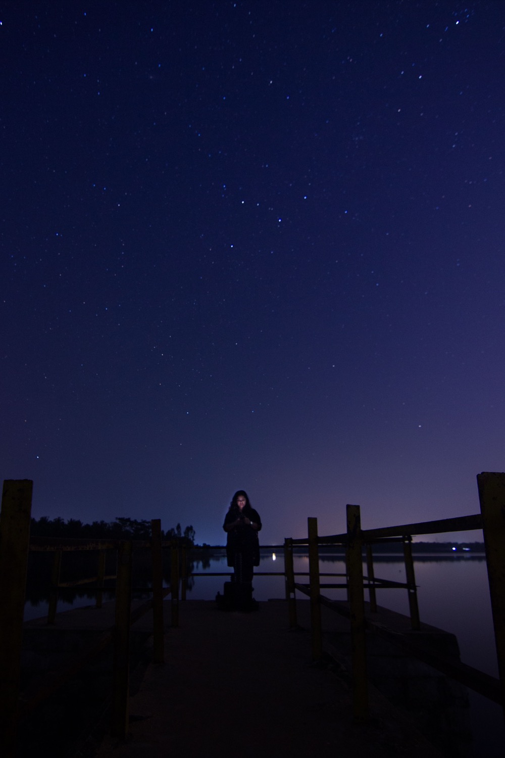 Figure standing on a dock under a starry sky