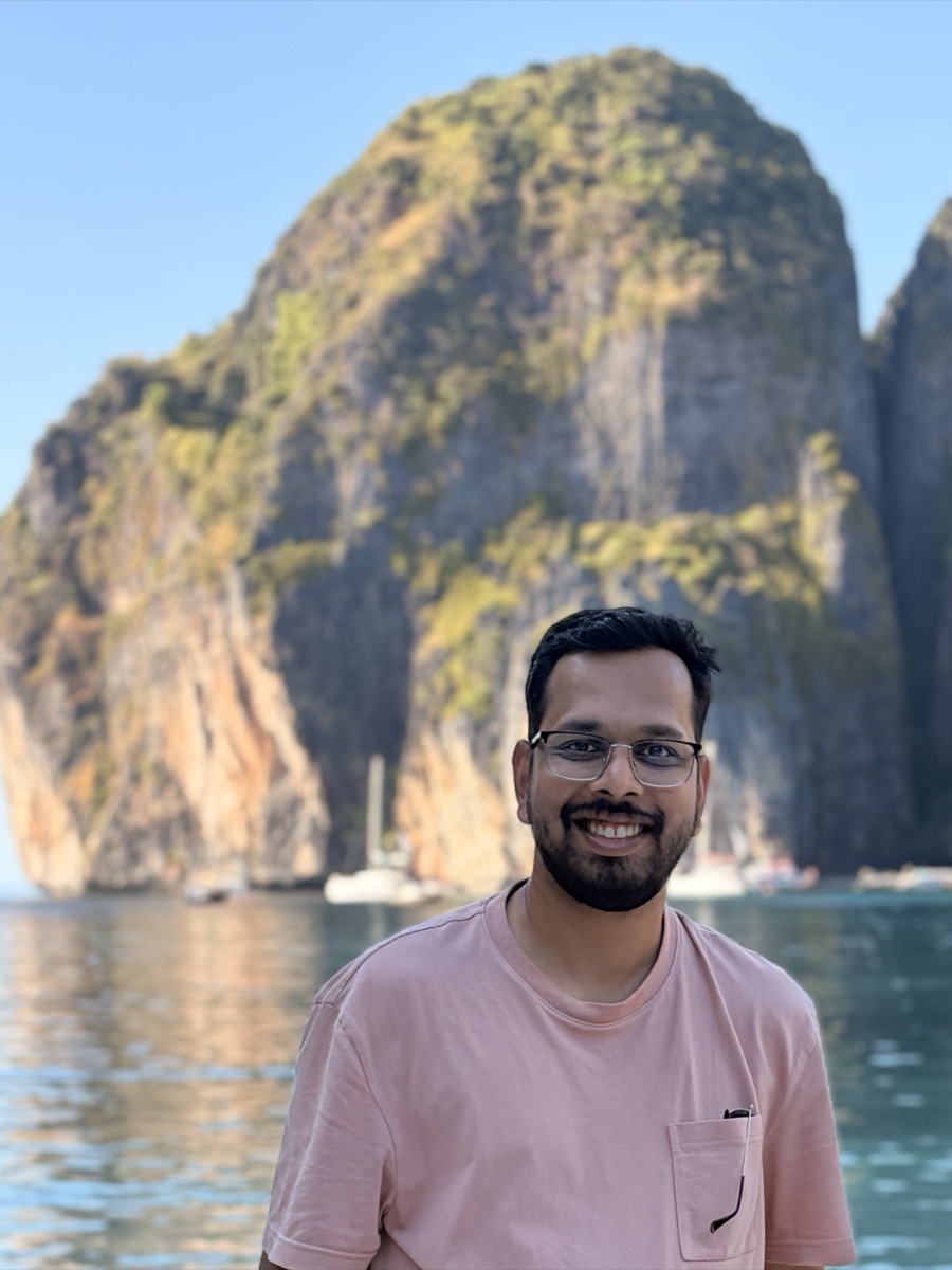 Pradeep, smiling, standing in front of limestone karst cliffs on a boat trip