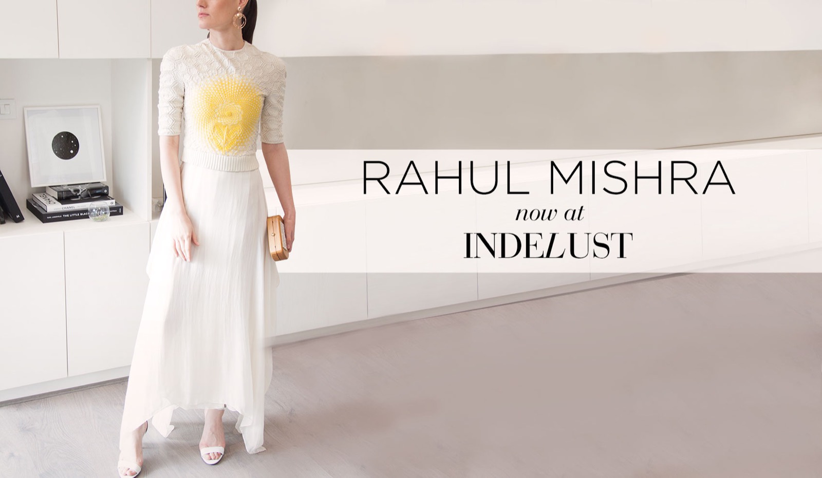 Indelust web banner announcing 'Rahul Mishra, now at Indelust', a model in white in a minimal interior.